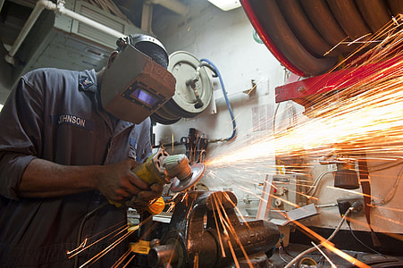man wearing gray welding mask while grinding metal using angle grinder thumbnail