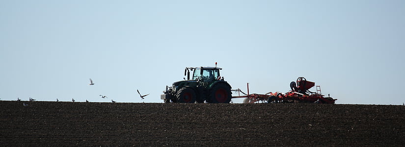 black tractor with cultivator on field thumbnail
