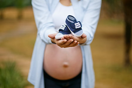 pregnant woman holding baby's blue shoes thumbnail