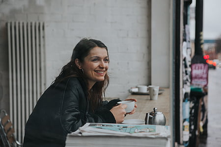 smiling woman while sitting on chair front of table thumbnail