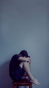 man sitting on brown wooden chair thumbnail