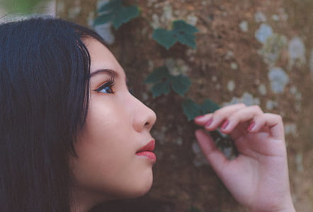 Close Up Photo of Woman Looking Up Near Tree Trunk thumbnail
