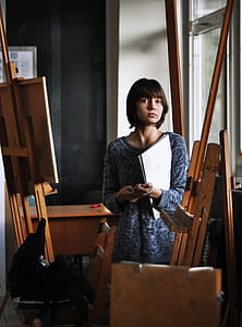 woman holds papers white standing near brown wood thumbnail