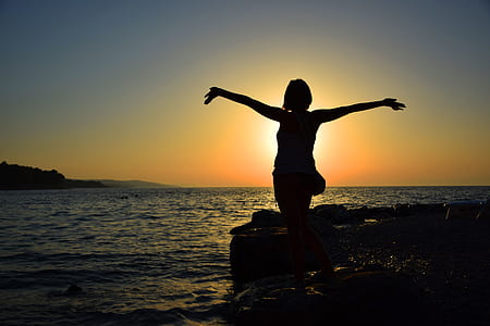 silhouette of woman beside of ocean during sunset thumbnail