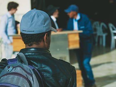 man wearing black leather jacket carrying gray backpack thumbnail