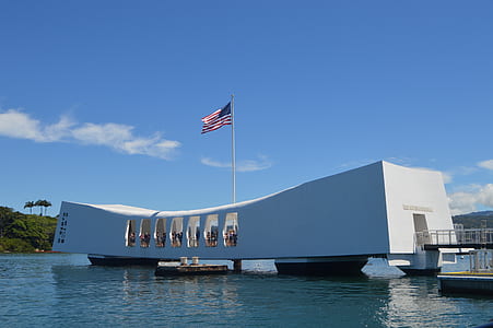 white concrete building with USA flag surrounded body of water at daytime thumbnail