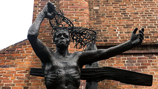 black concrete human statue outside brick building thumbnail