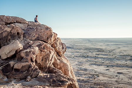 person sitting on cliff on mountain thumbnail