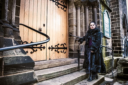 woman in black trench coat standing beside staircase railing thumbnail