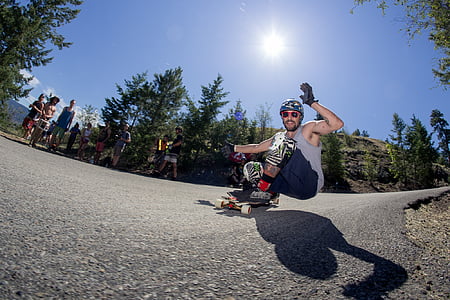 man in tank top riding on longboard at road thumbnail