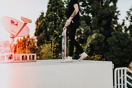 person standing on white surface holding skateboard near parabolic dish thumbnail
