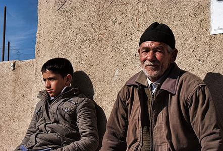 boy and man sitting and leaning against concrete wall thumbnail