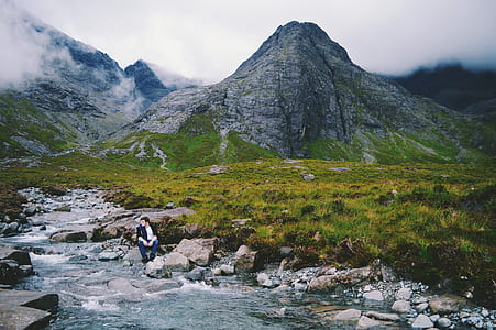 person sitting on gray rock on river thumbnail