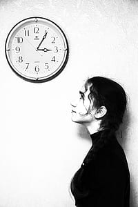 woman standing looking at wall clock thumbnail