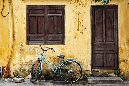 teal bicycle parked beside brown strucutre thumbnail