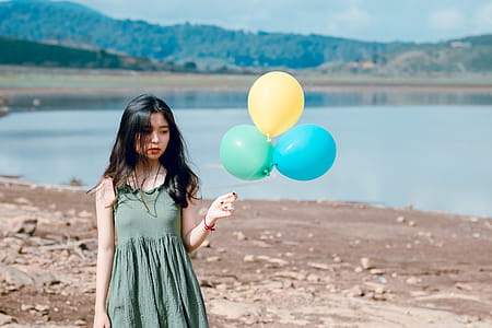 Woman in Green Sleeveless Dress Holding Three Balloons thumbnail