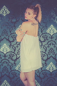 woman wearing white halter dress standing near damask graphic wallpaper thumbnail