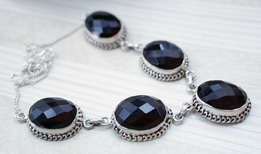 silver-colored black gemstone studded necklace on beige surface thumbnail
