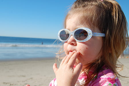 girl standing on seashore with fingers on mouth at daytime thumbnail