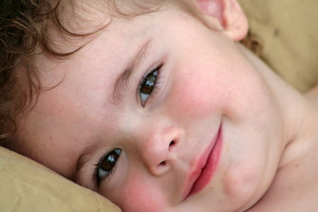 toddler smiling while laying on beige throw pillow thumbnail