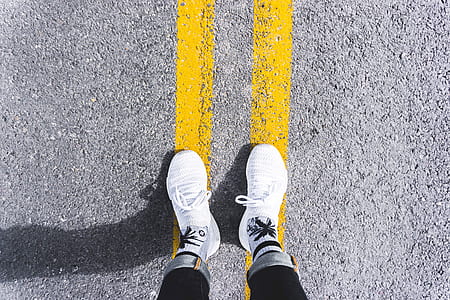 high-angle photography of person wearing shoes standing in yellow line thumbnail
