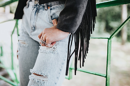 Blonde woman in a black jacket and ripped jeans by a green handrail thumbnail