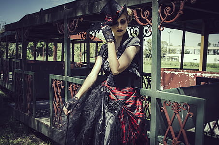 Woman in Black and Red Short-sleeved Dress Standing in Front of Green Steel Structure thumbnail
