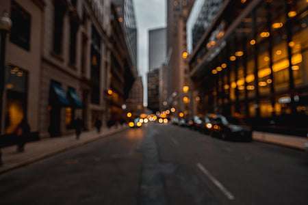 blur photography of vehicle parked at roadside near buildings at dusk thumbnail