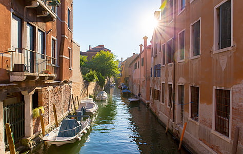 white boats on body of water beside brown buildings thumbnail