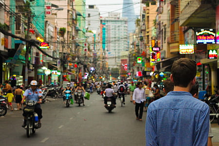 man wearing blue long-sleeved shirt walking on street during daytime thumbnail