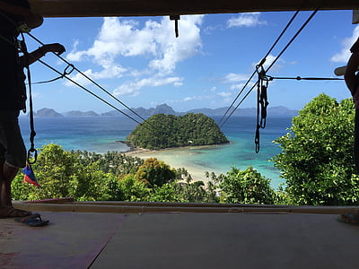 man standing while holding zipline cable during daytime thumbnail