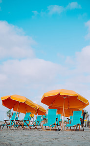 four orange parasol and with teal armchair lot on sand at daytime thumbnail