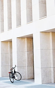 black bicycle parked in front of concrete building thumbnail