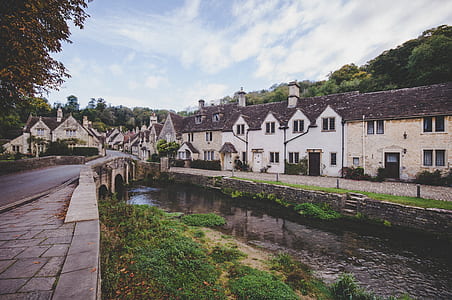 houses near body of water under cloudy blue sky thumbnail