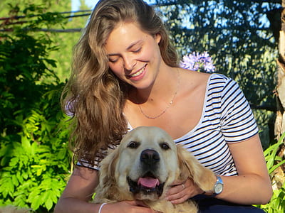 woman wearing white and black scoop-neck shirt holding adult yellow Labrador retriever thumbnail