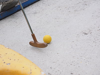 brown golf putter near yellow golf ball on white floor thumbnail