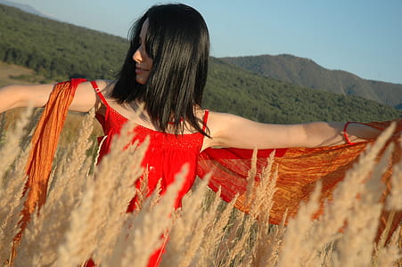 woman in grass field near mountain thumbnail