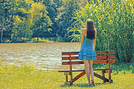 Girl in Blue Dress standing by a bench by a lake thumbnail