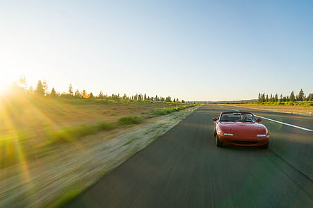 red Mazda Miata convertible on road thumbnail