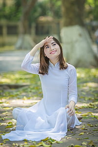 woman wearing white long-sleeved dress sitting on pavement looking up thumbnail