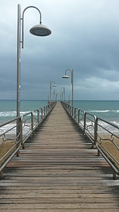 brown wooden dock below grey cloudy skies near sea water thumbnail