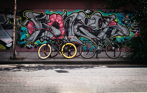 two black and and yellow bikes near wall with graffiti thumbnail