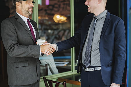 two person handshaking near clear glass storefront during daytime thumbnail