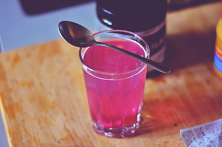 filled clear drinking glass on top of brown table thumbnail