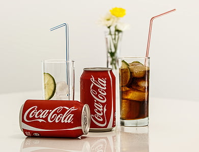 two Coca-Cola cans beside drinking glass thumbnail