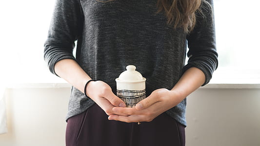 person holding white and gray ceramic mug with lid thumbnail