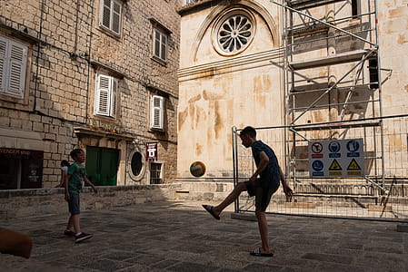 Two Boys Playing Ball Near Building thumbnail