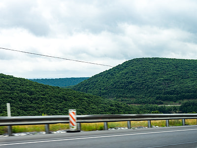 road beside green grass mountains thumbnail
