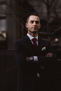 man in black suit jacket hands on chest thumbnail