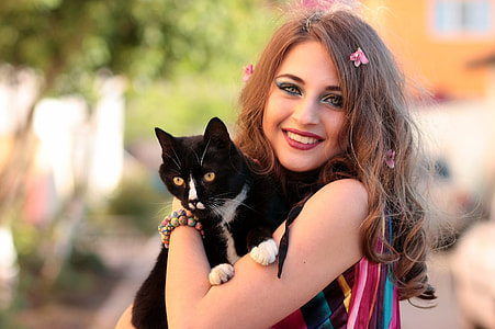 focus photography of woman carrying tuxedo cat during daytime thumbnail